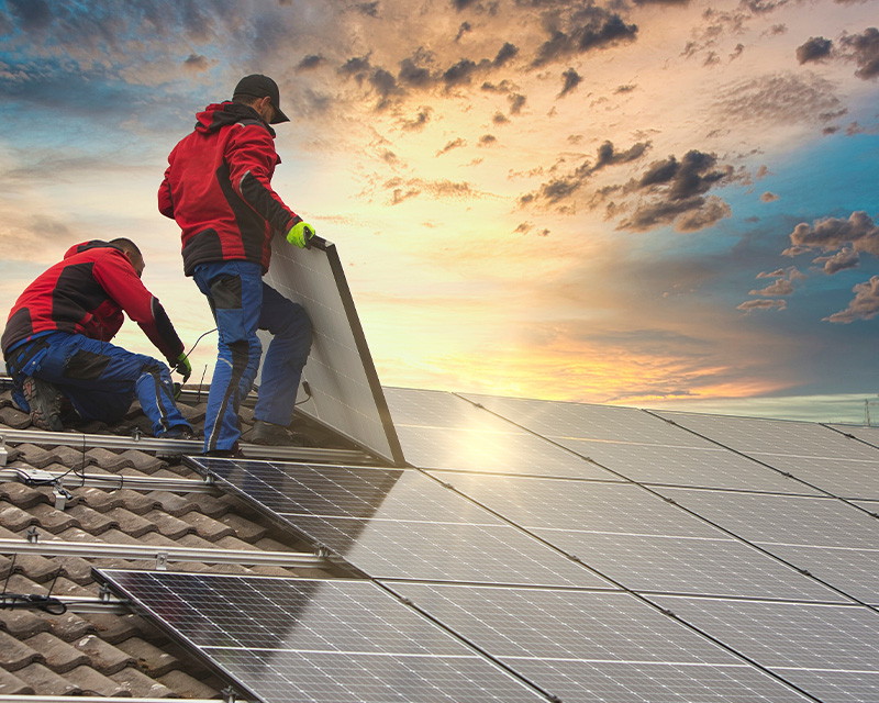 two technicians installing solar panels on a roof at sunset with twelve solar panels for energy efficiency