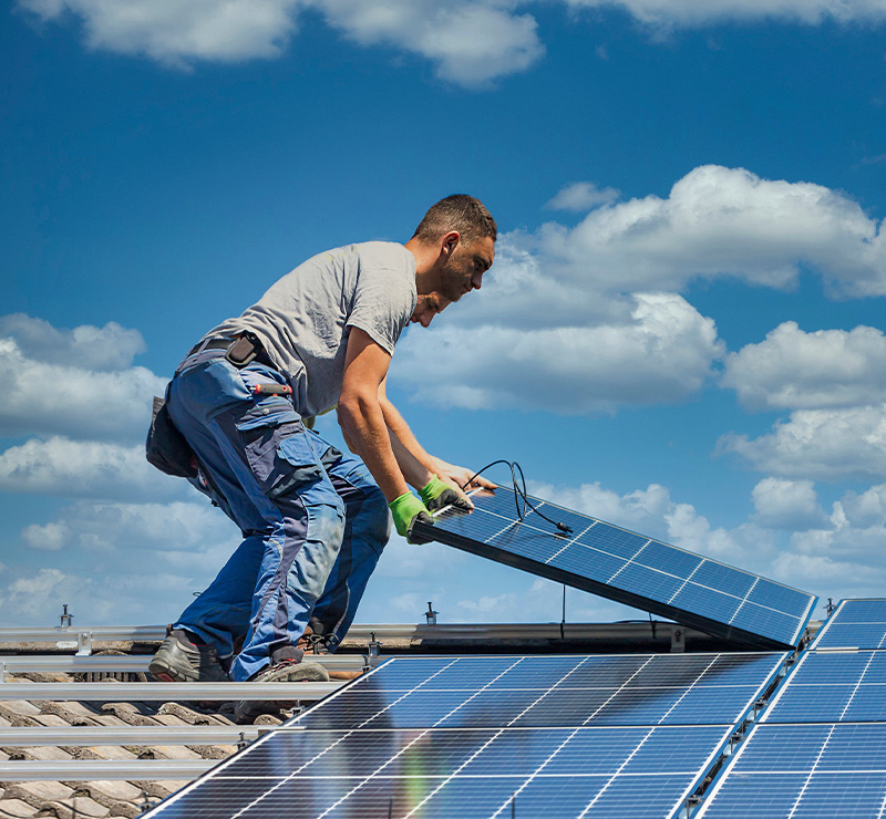 man pointing at solar panels on roof of house in rural area showing interest in solar energy solutions for homes