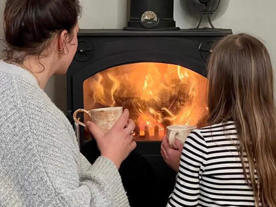 two people enjoying warmth by the fire with cozy mugs